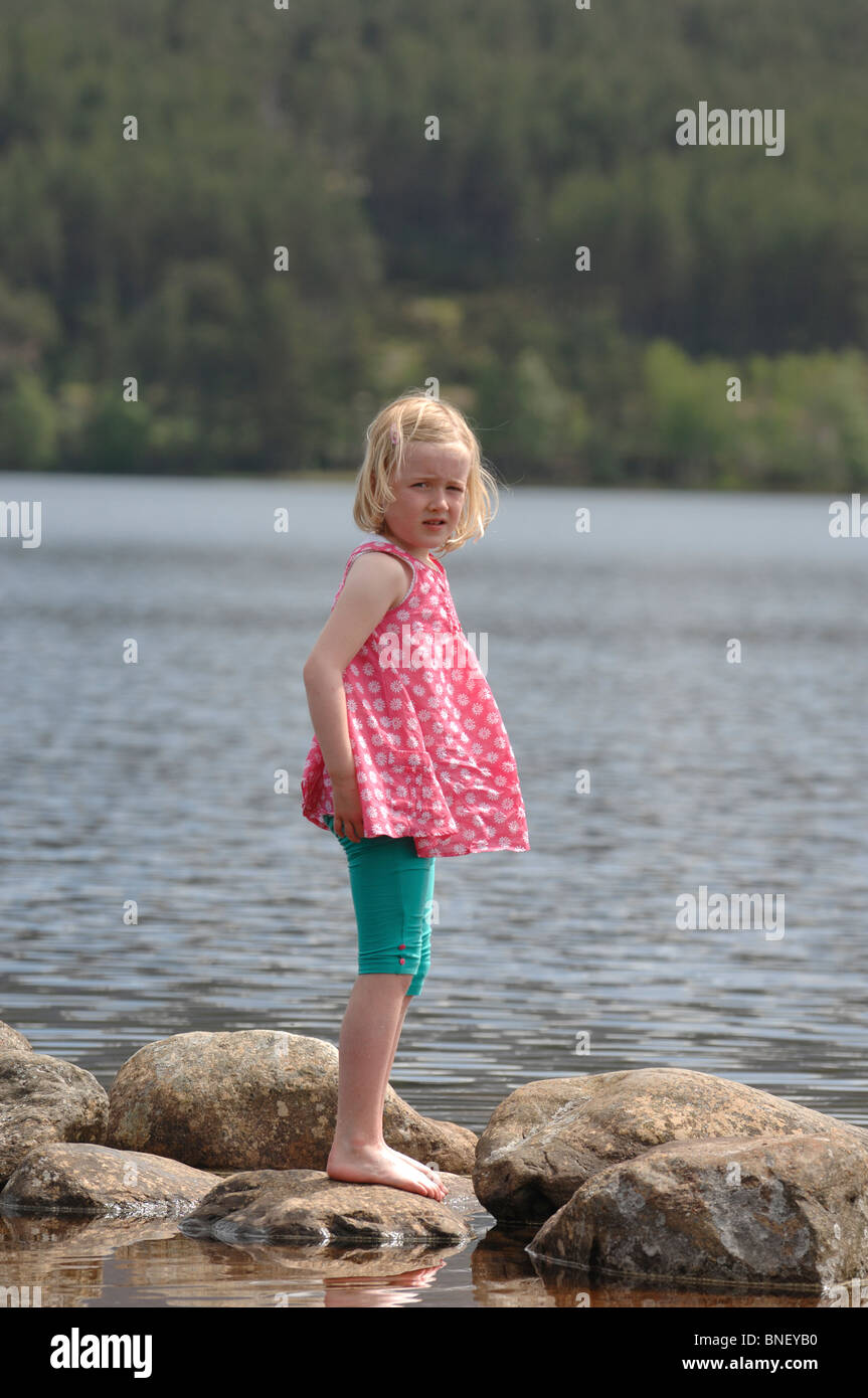 Eine junge Blondine in ein rosa Top und türkisen Leggings paddeln am Ufer des Loch Morlich in der Nähe von Aviemore Inverness-shire Stockfoto