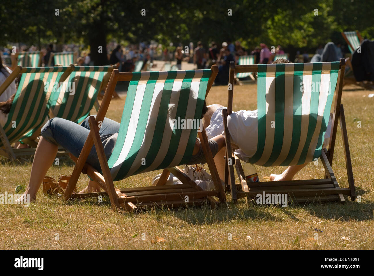 Liegestühle Paar Genießen Sie die Sommersonne während einer Mini-Hitzewelle heißes Wetter Hyde Park London UK Klimawandel 2010, 2010s HOMER SYKES Stockfoto