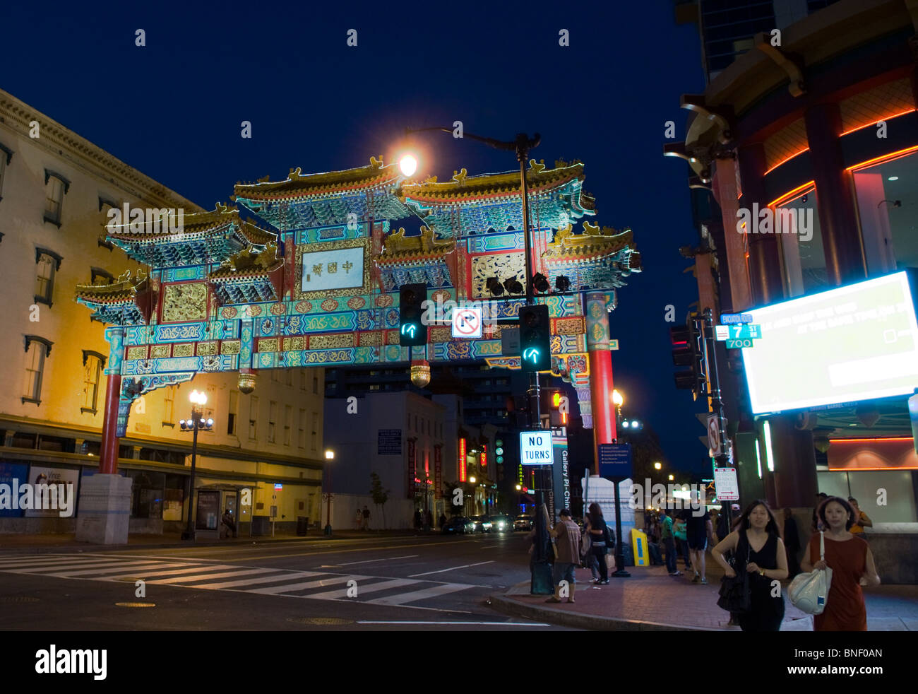 Zwei Damen über die Straße am Gallery in Washington DC mit dem Chinatown Torbogen im Hintergrund statt. Stockfoto