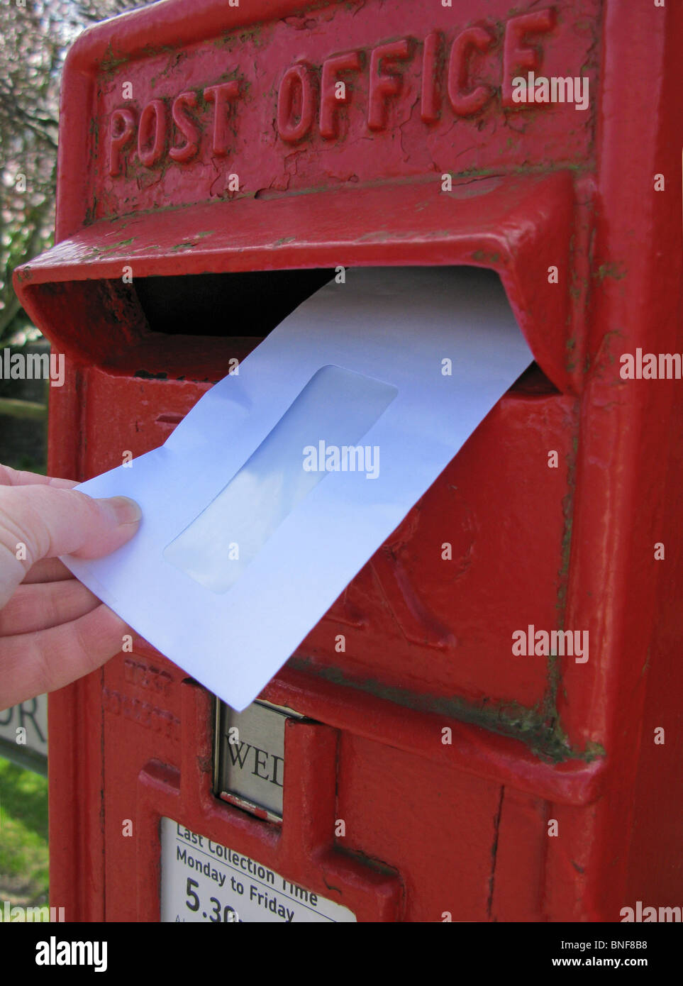 Frau einen Brief in einen roten Briefkasten buchen Stockfoto