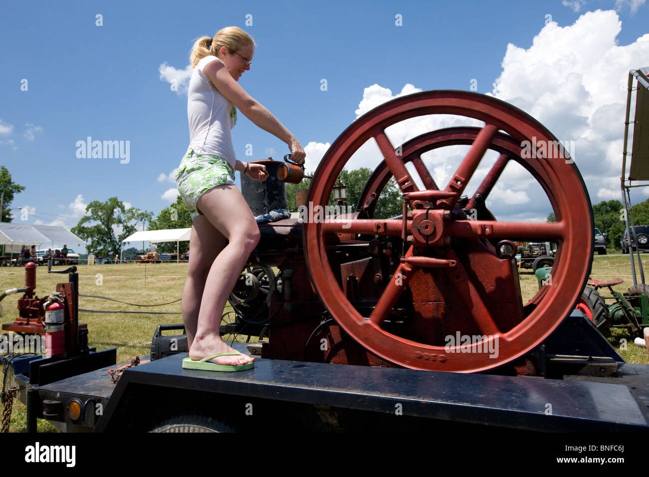 Mädchen einen internationalen sechs Pferd Motor an einem antiken Gas und Dampfmaschine Ölen zeigen bei Fort Hunter am Erie-Kanal. Stockfoto