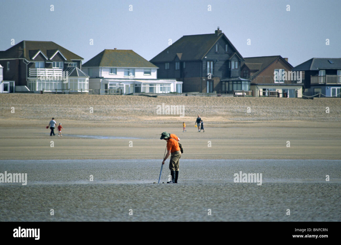 Mann mit Pfeife, die auf der Suche nach Muscheln, Camber Sands in der Nähe von Roggen, East Sussex, UK Stockfoto