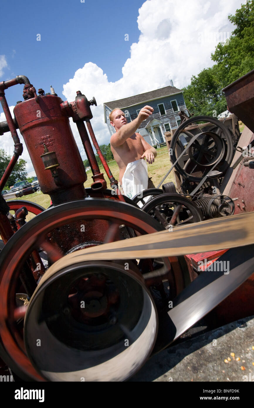 Mann einen Mais schälen Maschine bei einem antiken Gas und Dampf-Motor Show in Fort Hunter am Erie-Kanal in Betrieb. Stockfoto