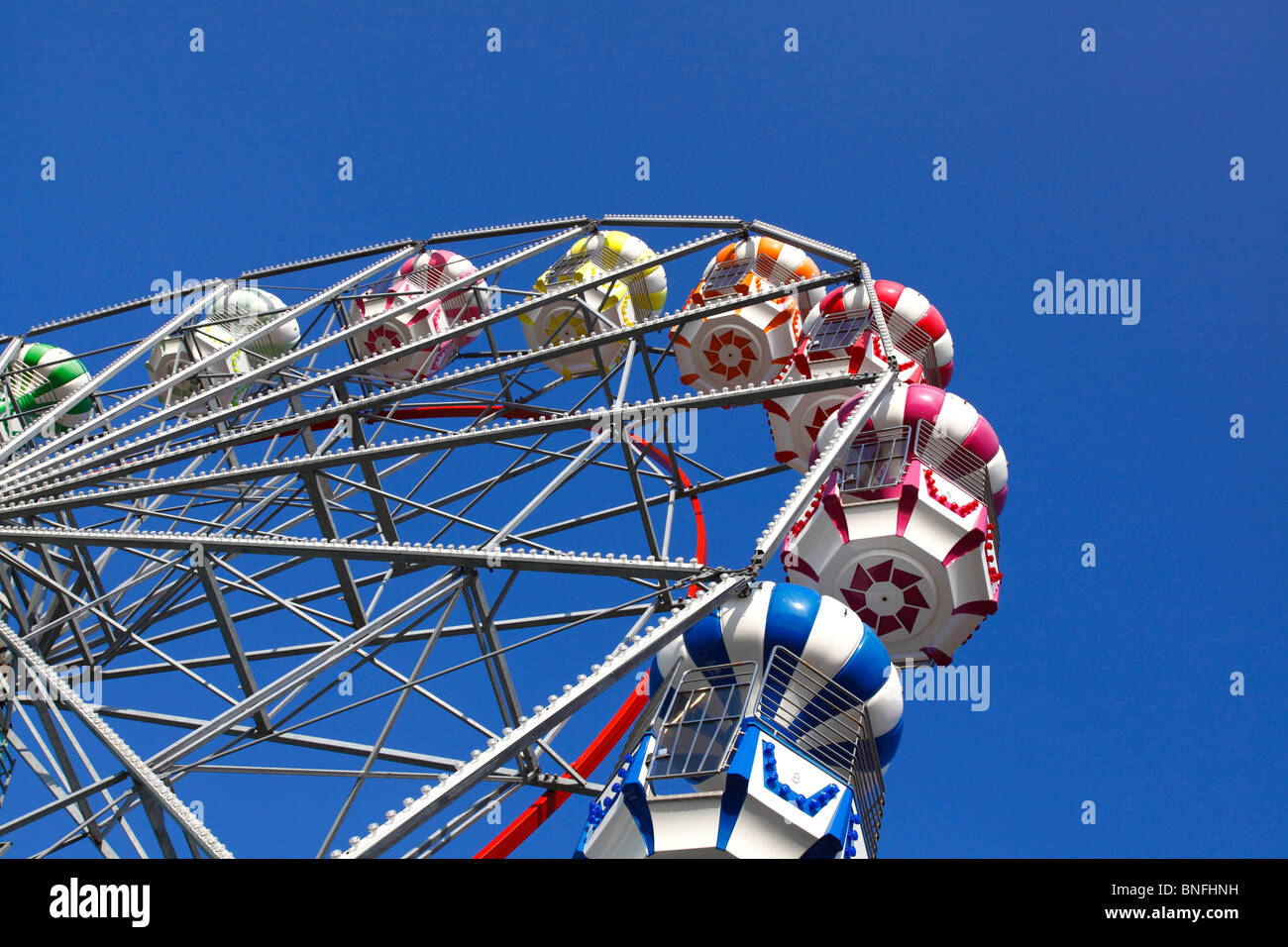 Ein großes Rad gegen einen schönen klaren blauen Himmel auf der Kirmes am Meer. Stockfoto