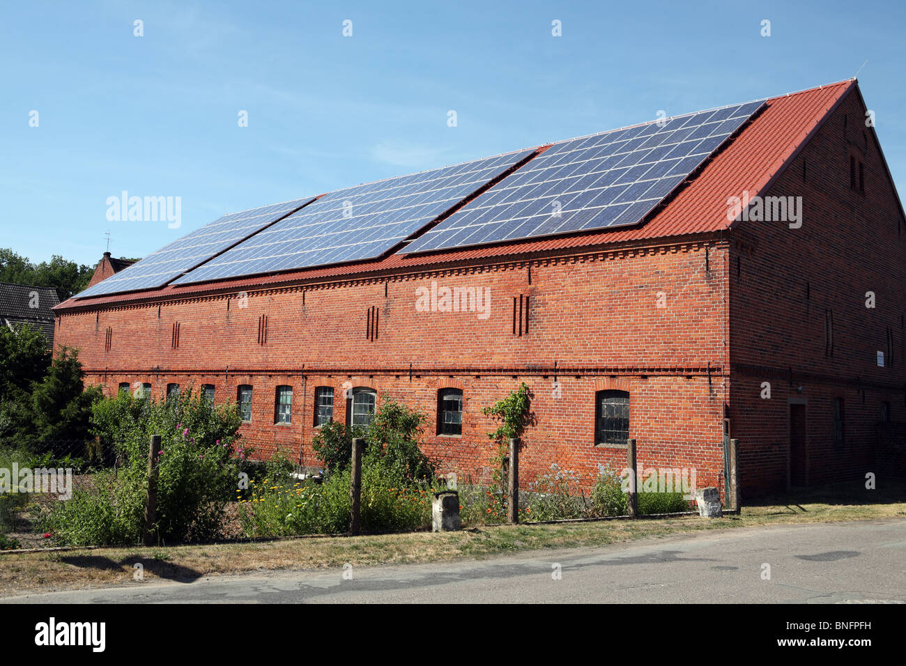 Eine Scheune, deren Dach mit Photovoltaik oder Sonnenkollektoren zur Stromerzeugung innerhalb des Dorfes Bälow, Deutschlands bedeckt ist. Stockfoto