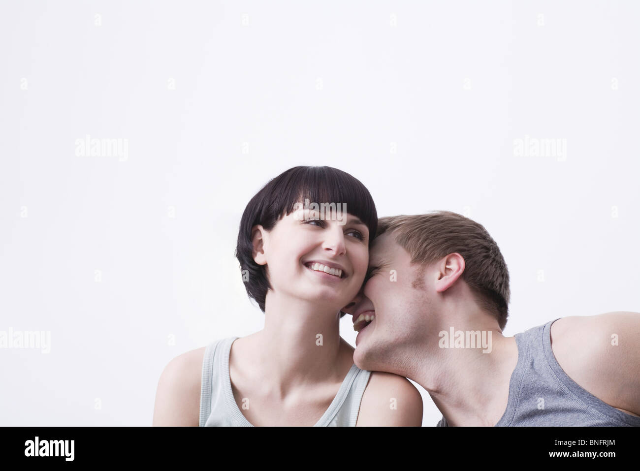 Junges Paar sitzen lachend in Weste Tops, Exemplar Stockfoto