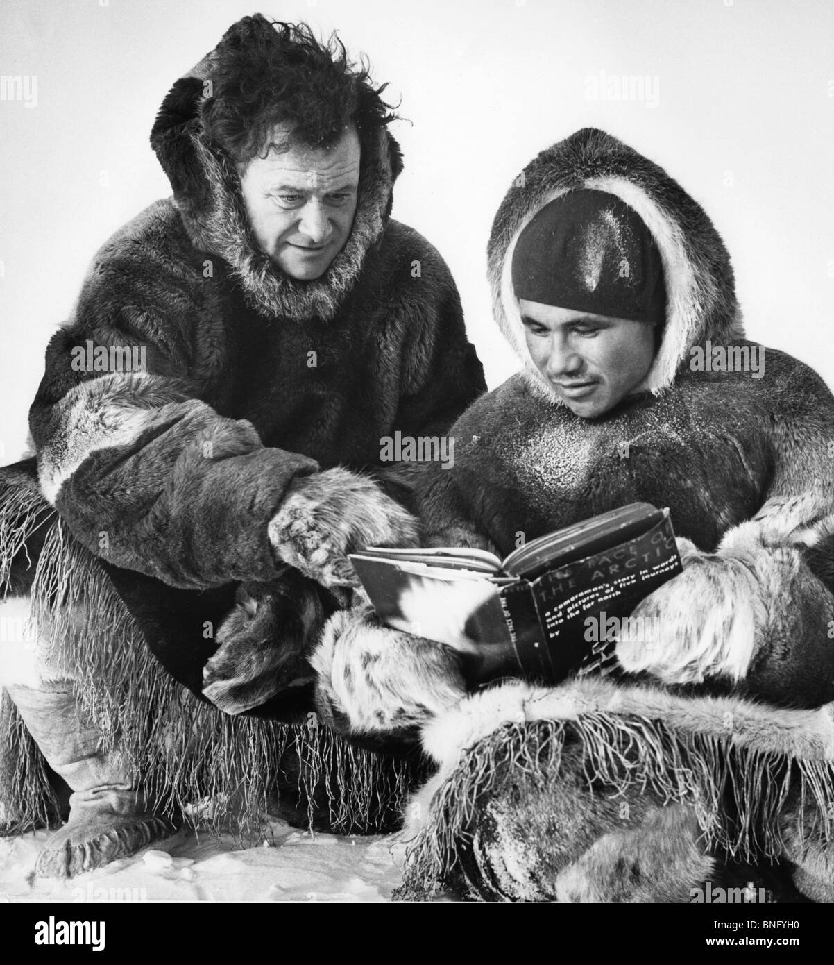 Arktis, zwei Männer im Pelz sitzen und lesen Buch Stockfoto