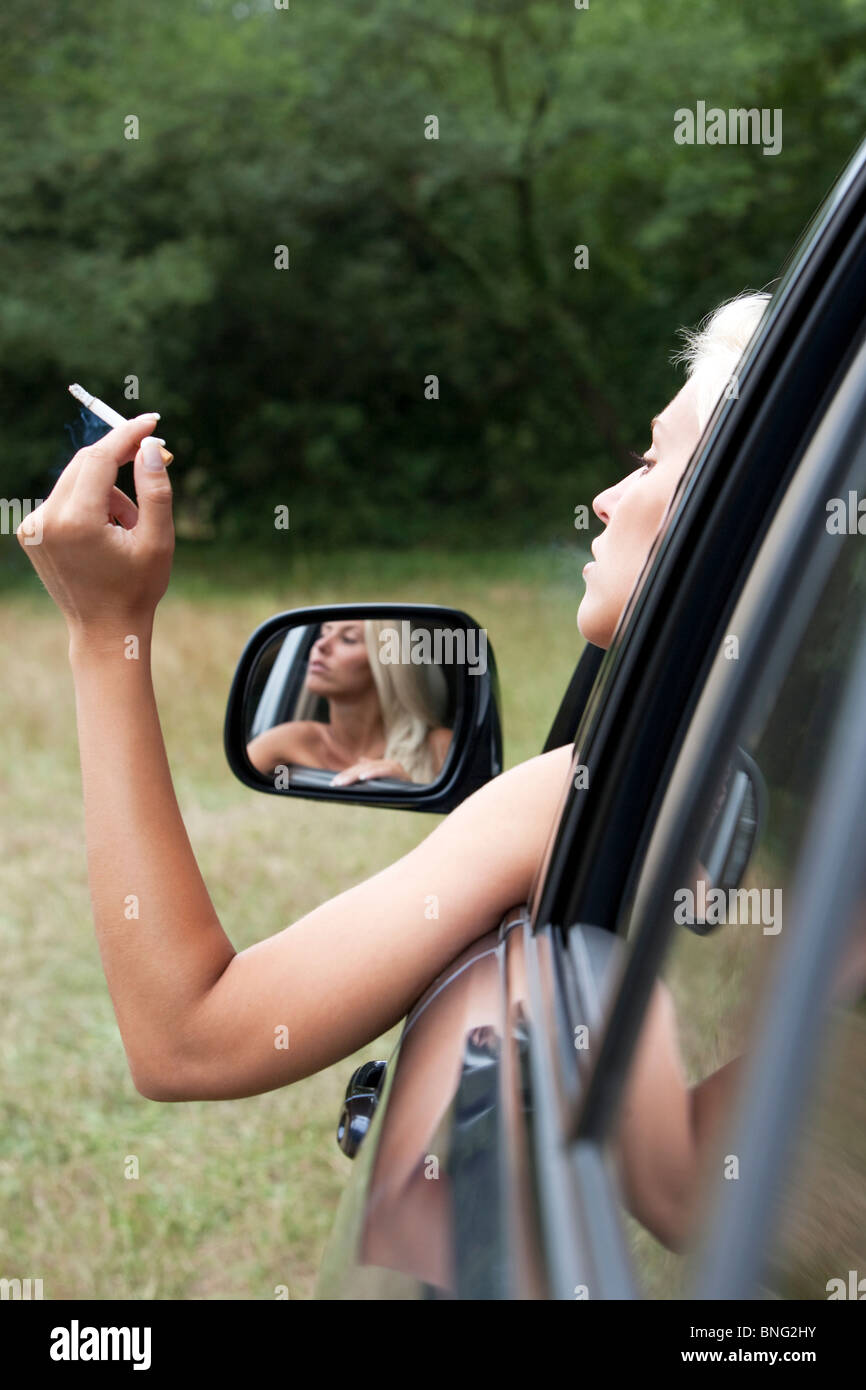 Frau, die raucht aus dem Fenster eines Autos Stockfoto