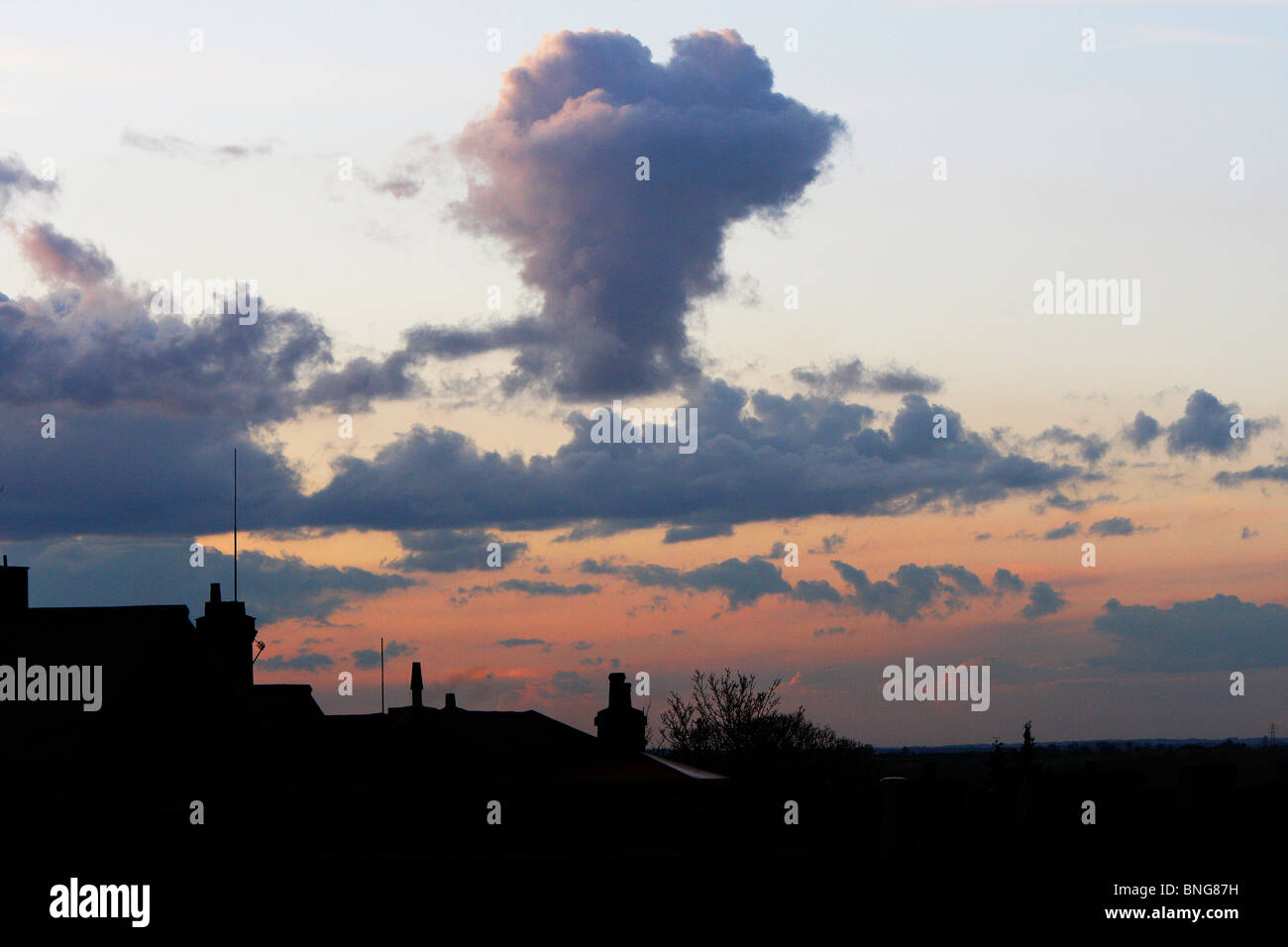 Herzförmige Wolke beim Sonnenuntergang über Silhouette Dächer in Epping, Essex, UK Stockfoto