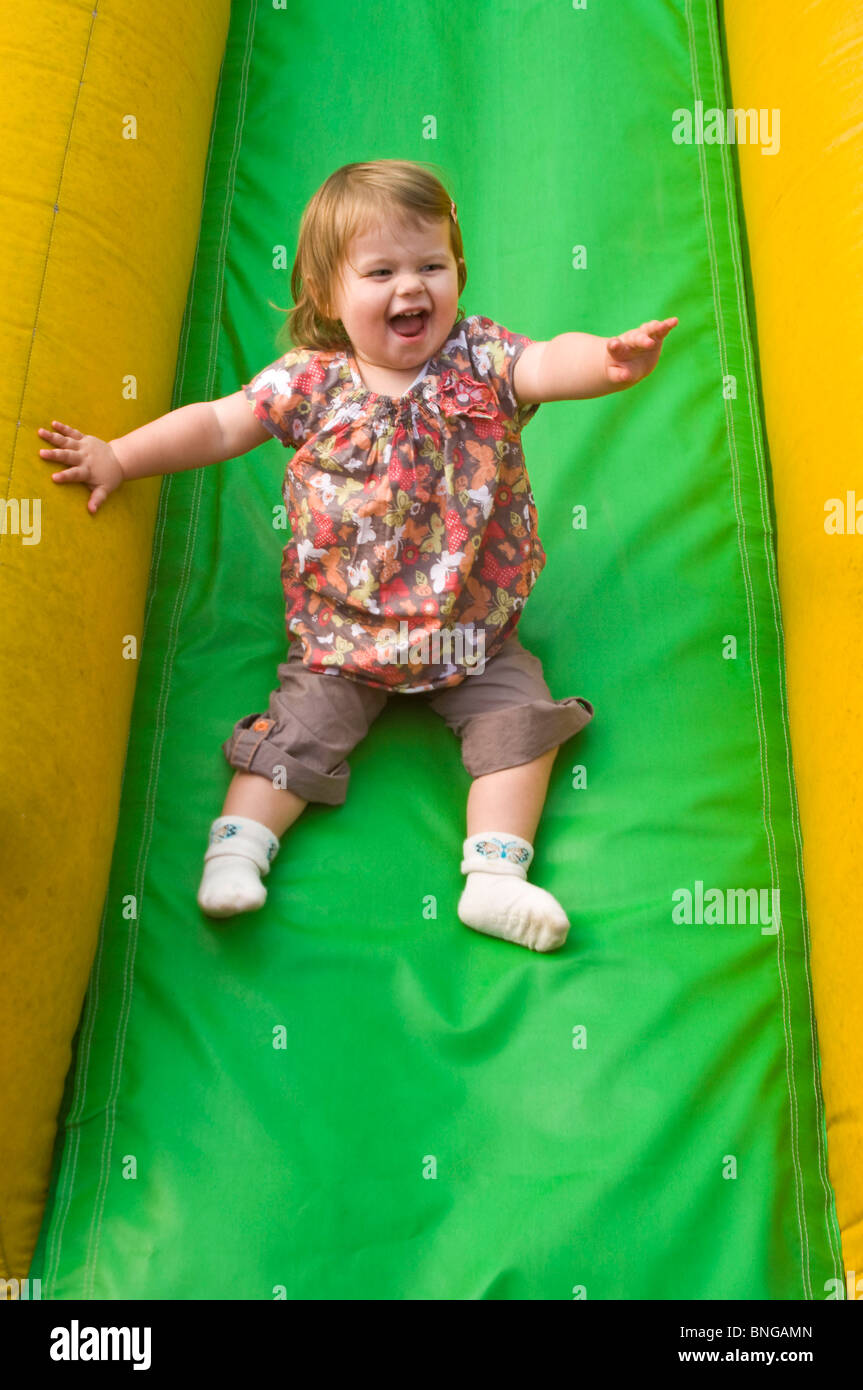 Vertikale Porträt eines Mädchens mit viel Spaß eine inflatible Folie auf eine weiche Spielplatz rutschen. Stockfoto
