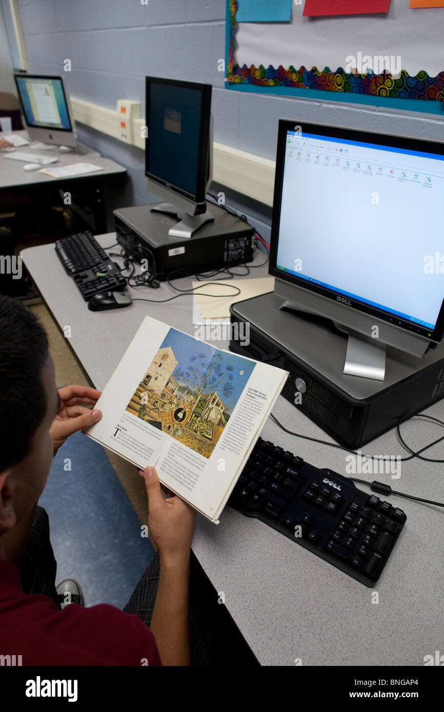 Student befasst sich mit Informationen über Künstler Joan Miro in Buch vor mit Computer, Online-Internet-Recherche zu diesem Thema zu tun Stockfoto