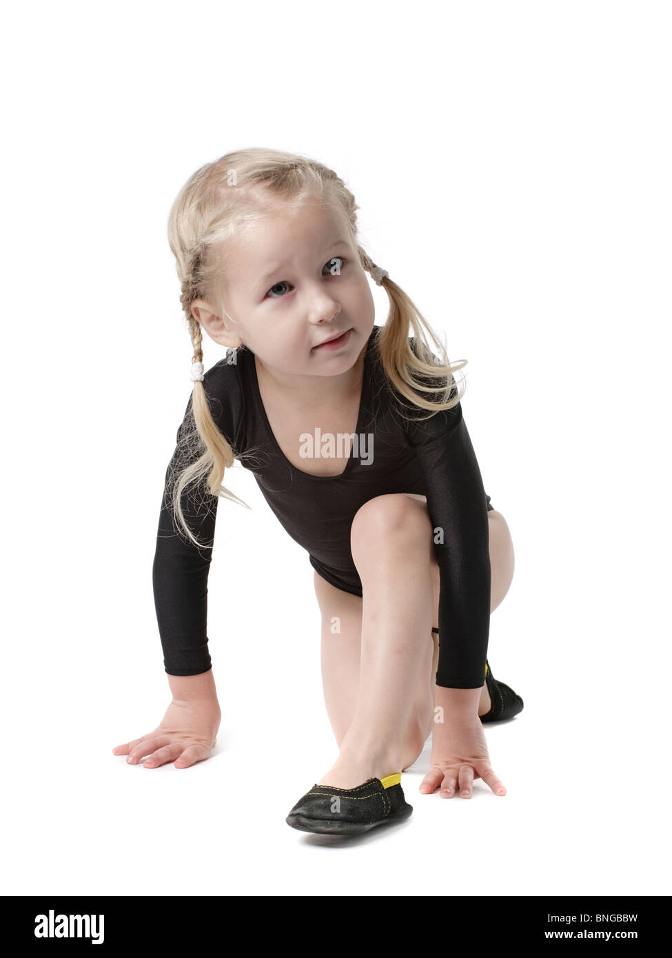 kleines Mädchen in Body für Rhythmische Sportgymnastik versucht den Spagat, isoliert auf weiss Stockfoto