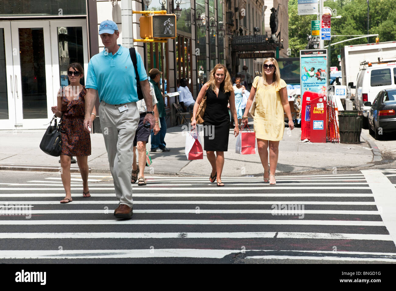 Fußgänger, darunter zwei hübsche Freundinnen in Sommerkleidern identisch Einkaufstaschen tragen überqueren 57th Street New York City Stockfoto