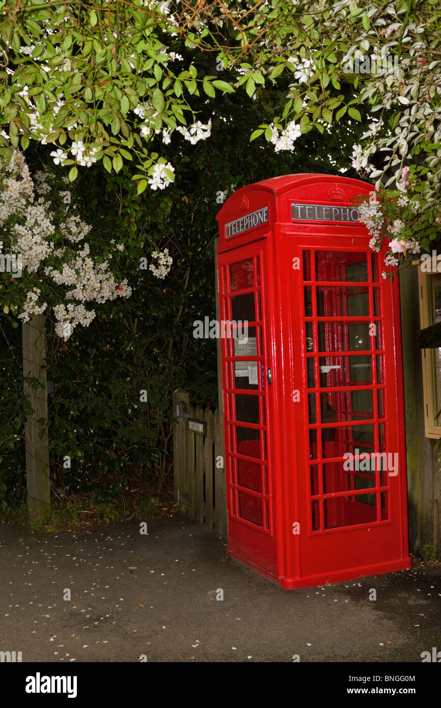 Eine gepflegte rote Telefonzelle in einem Garten in Cornwall Stockfoto