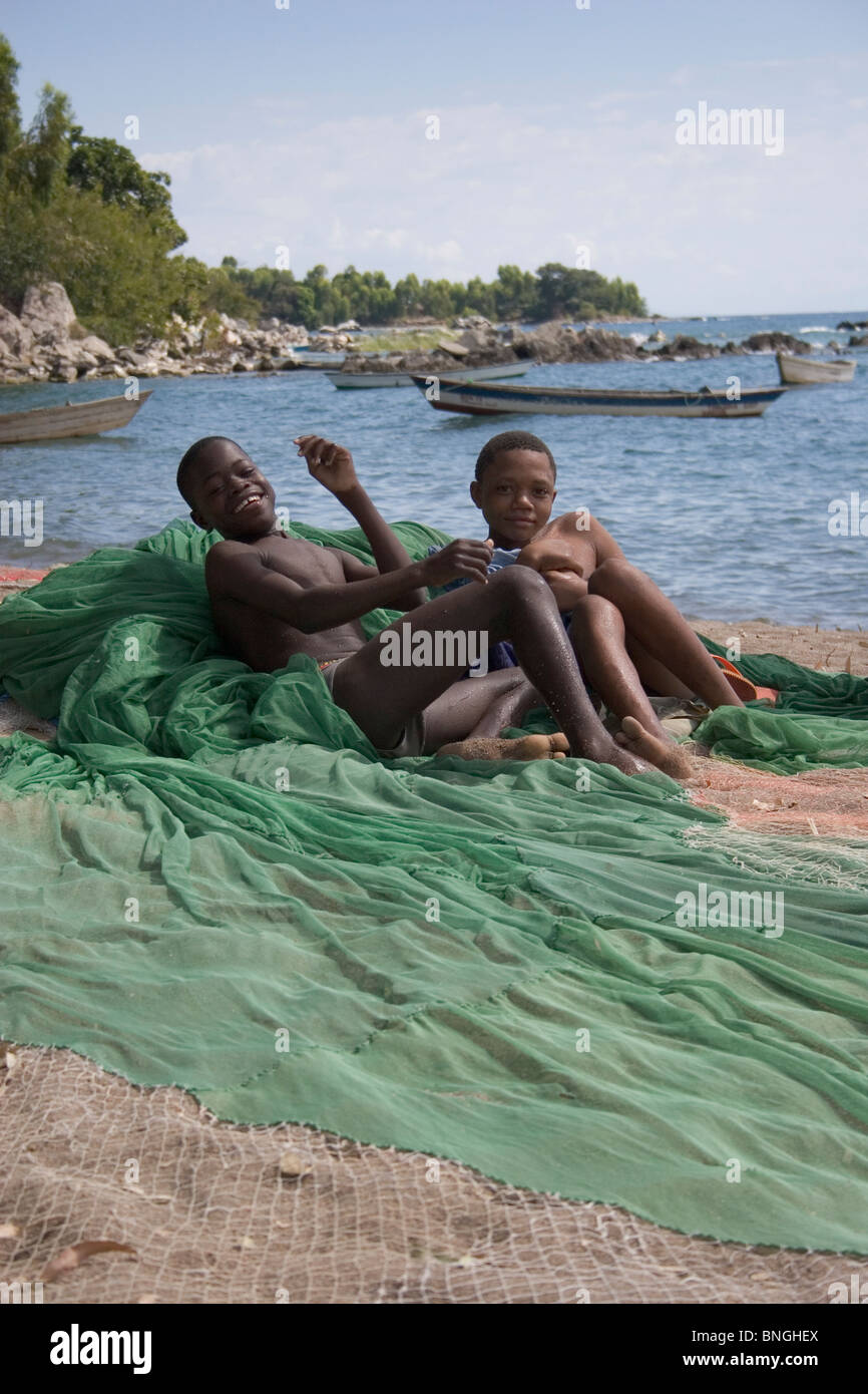 Malawische jungen entspannend auf Fischernetze ausgebreitet, um zu trocknen und am Strand, beiden Insel, Malawi behoben werden Stockfoto