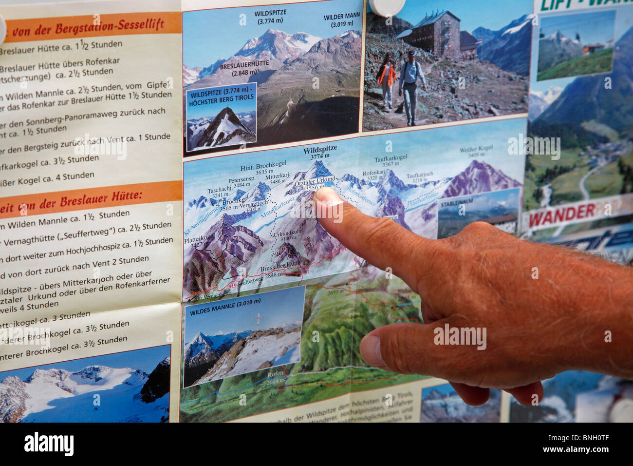 Ein Trekker deutet auf Wildspitze auf Trekking- und touristische Informationen-Plakatwand in Vent in der Nähe von Sölden in Österreich. Stockfoto