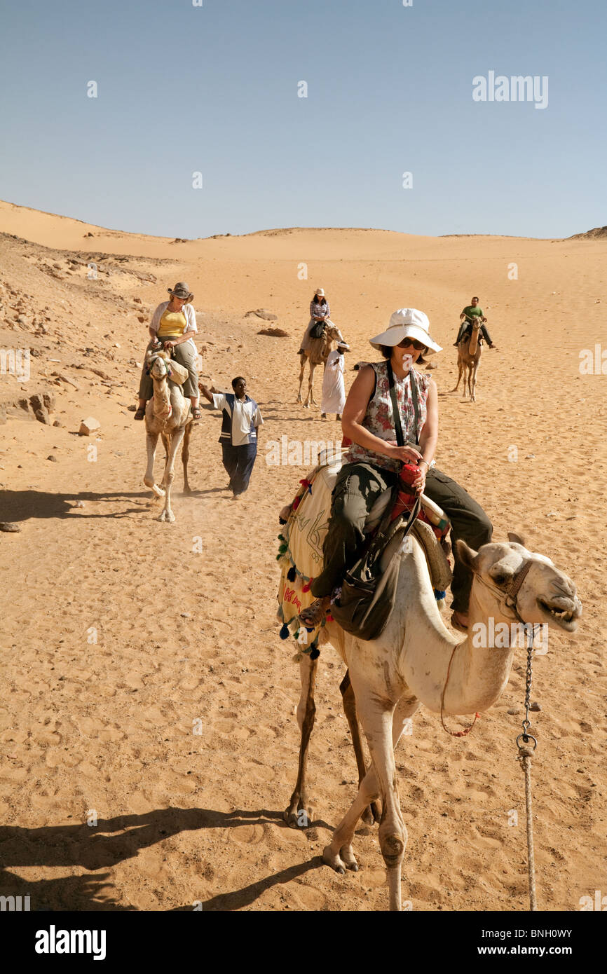 Ägypten Tourismus; Touristen, die Kamele in der Wüste in der Nähe von Assuan, Oberägypten Afrika reiten Stockfoto