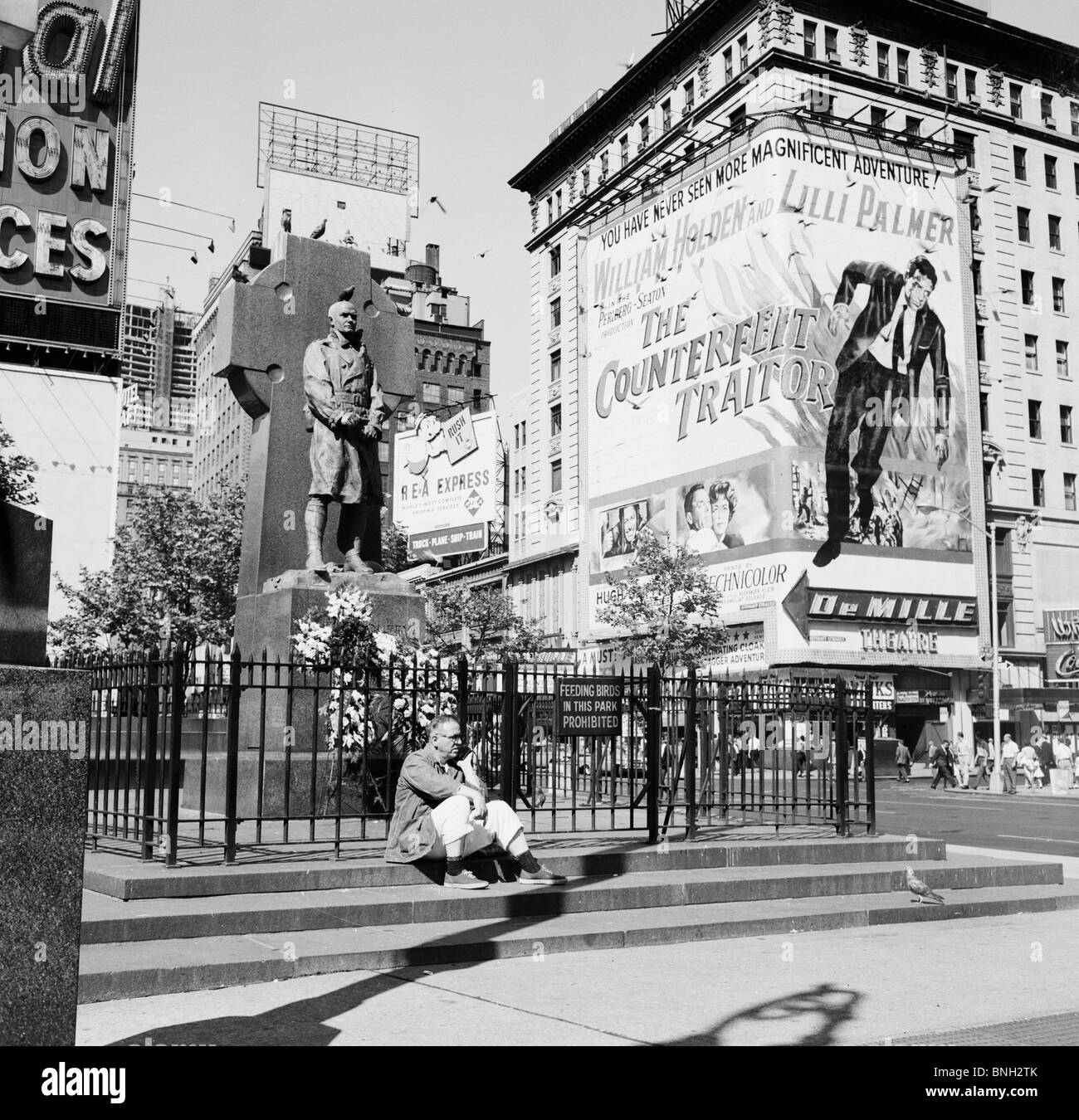 Mann sitzt vor einer Statue Vater Duffy Denkmal, Times Square, Manhattan, New York City, New York, USA Stockfoto