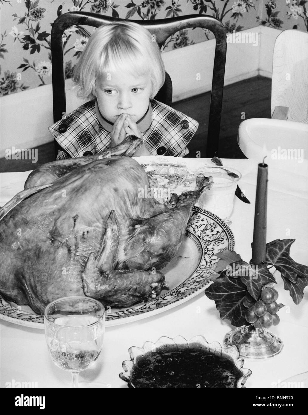 Erhöhte Ansicht von einem Mädchen sitzen am Esstisch und Blick auf einen Truthahn an Thanksgiving Tag Stockfoto