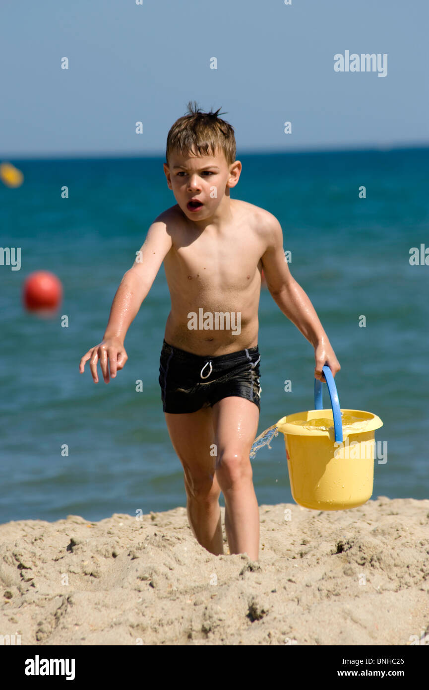 Jungen spielen mit Eimer am Strand Stockfoto