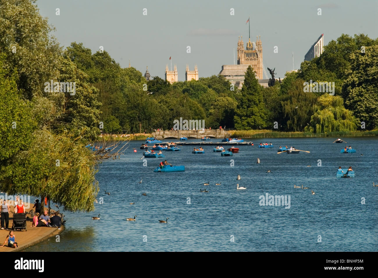 Serpentine Lake, Hyde Park Central London UK.Touristen zu Fuß rund um den See. Houses of Parliament im Hintergrund. 2010 HOMER SYKES Stockfoto