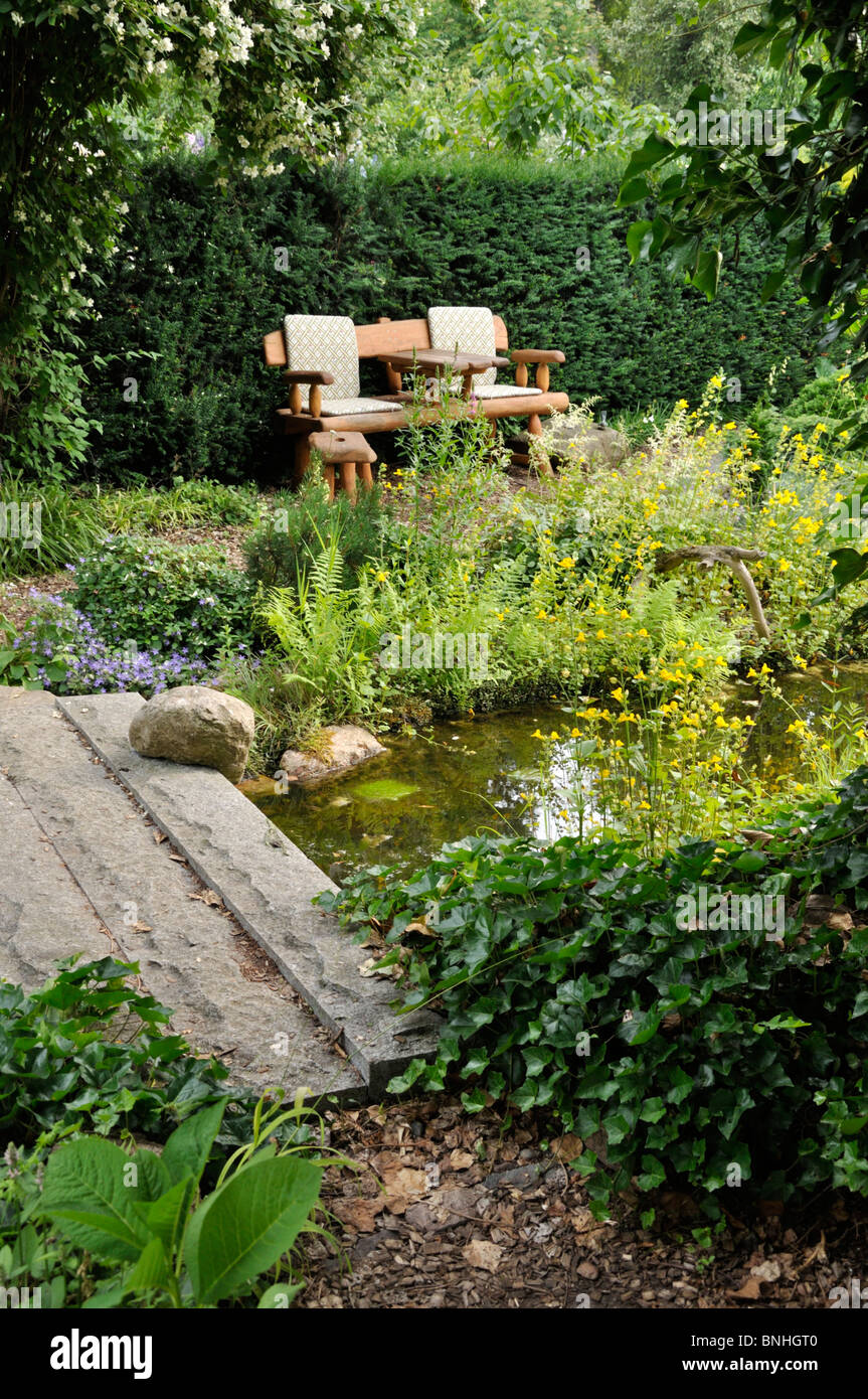 Garten Bank an einem Teich mit Brücke aus Stein. Design: Marianne und Detlef lüdke Stockfoto
