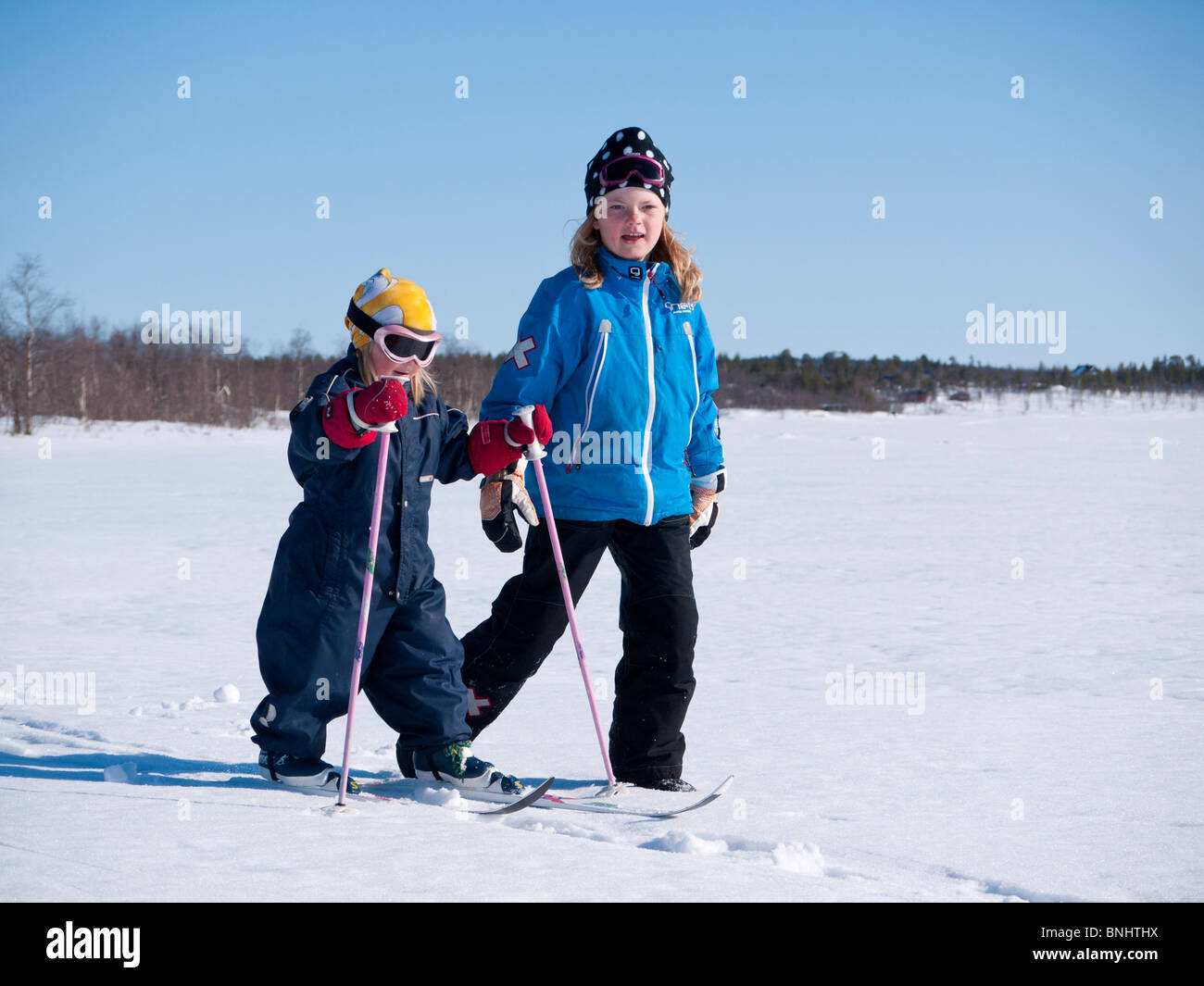 Zwei Schwestern, drei und acht Jahre alt, Spaziergang im Schnee in Kiruna, Lappland, Nordschweden. Stockfoto
