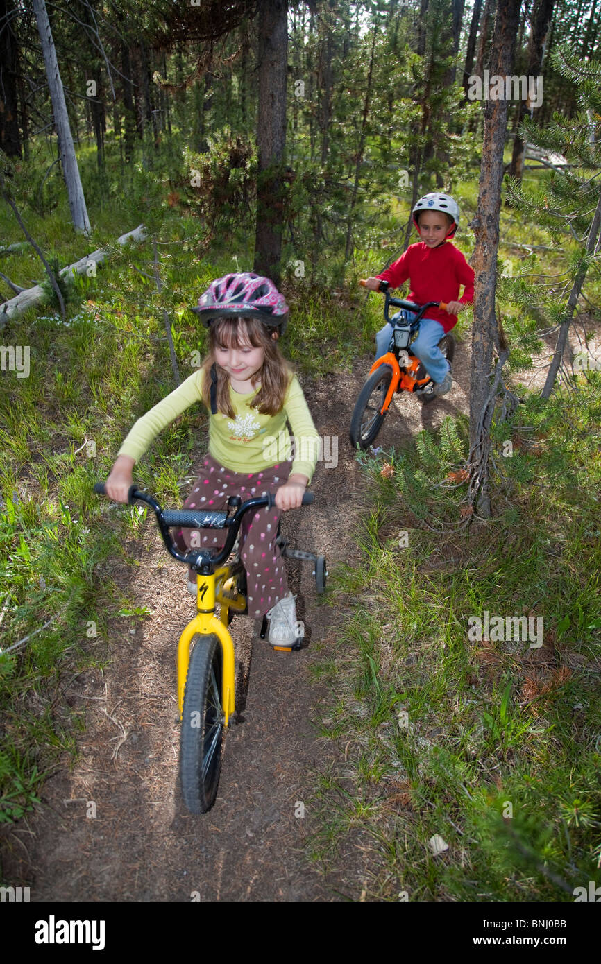 Kinder Fahrrad durch Wald fahren. Stockfoto