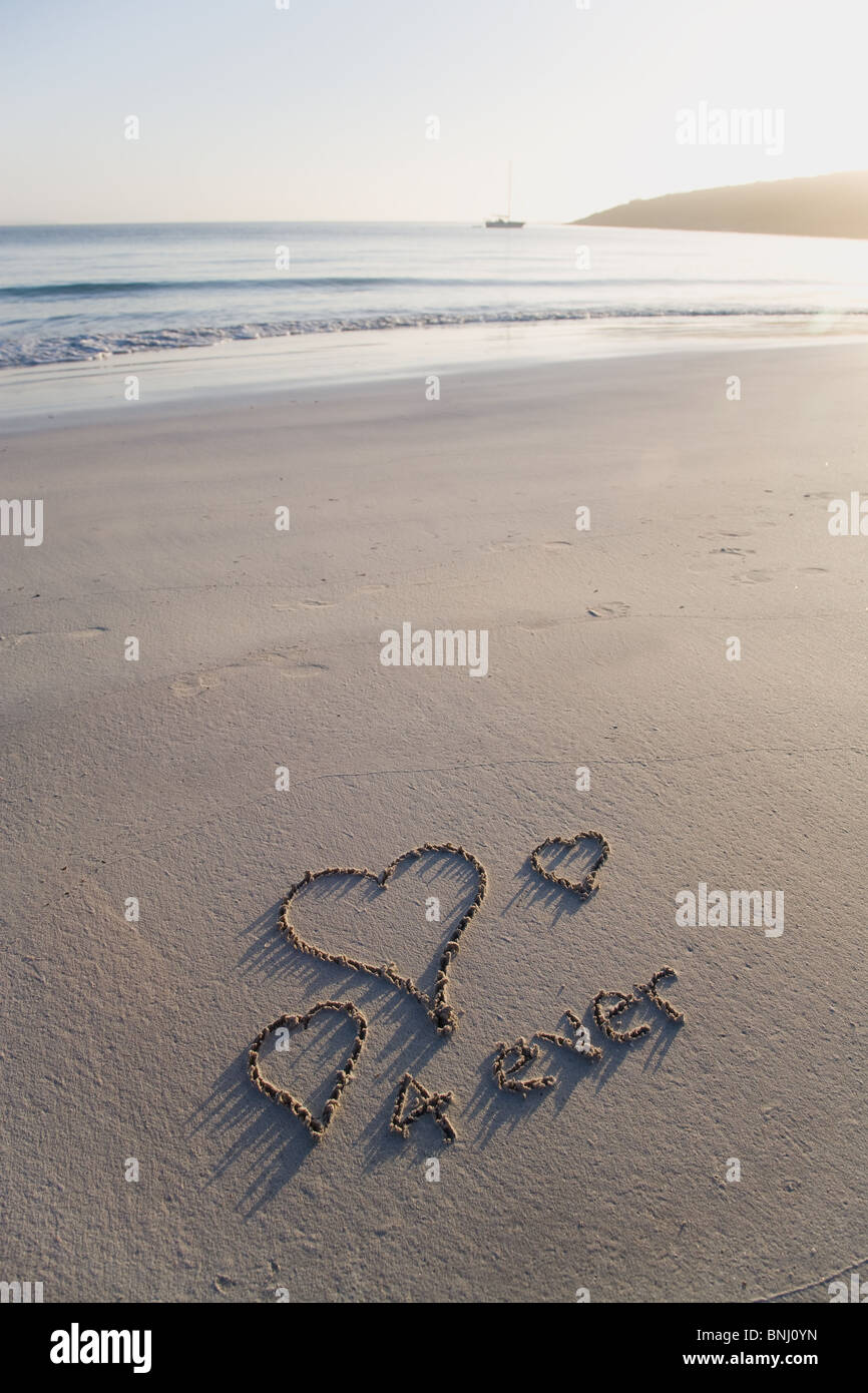 Liebe, Herzen und für immer an einem unberührten Strand geschrieben Stockfoto