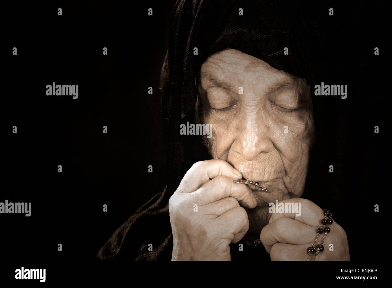 Alte Frau tief im Gebet tragen einen schwarzen Schleier Stockfoto
