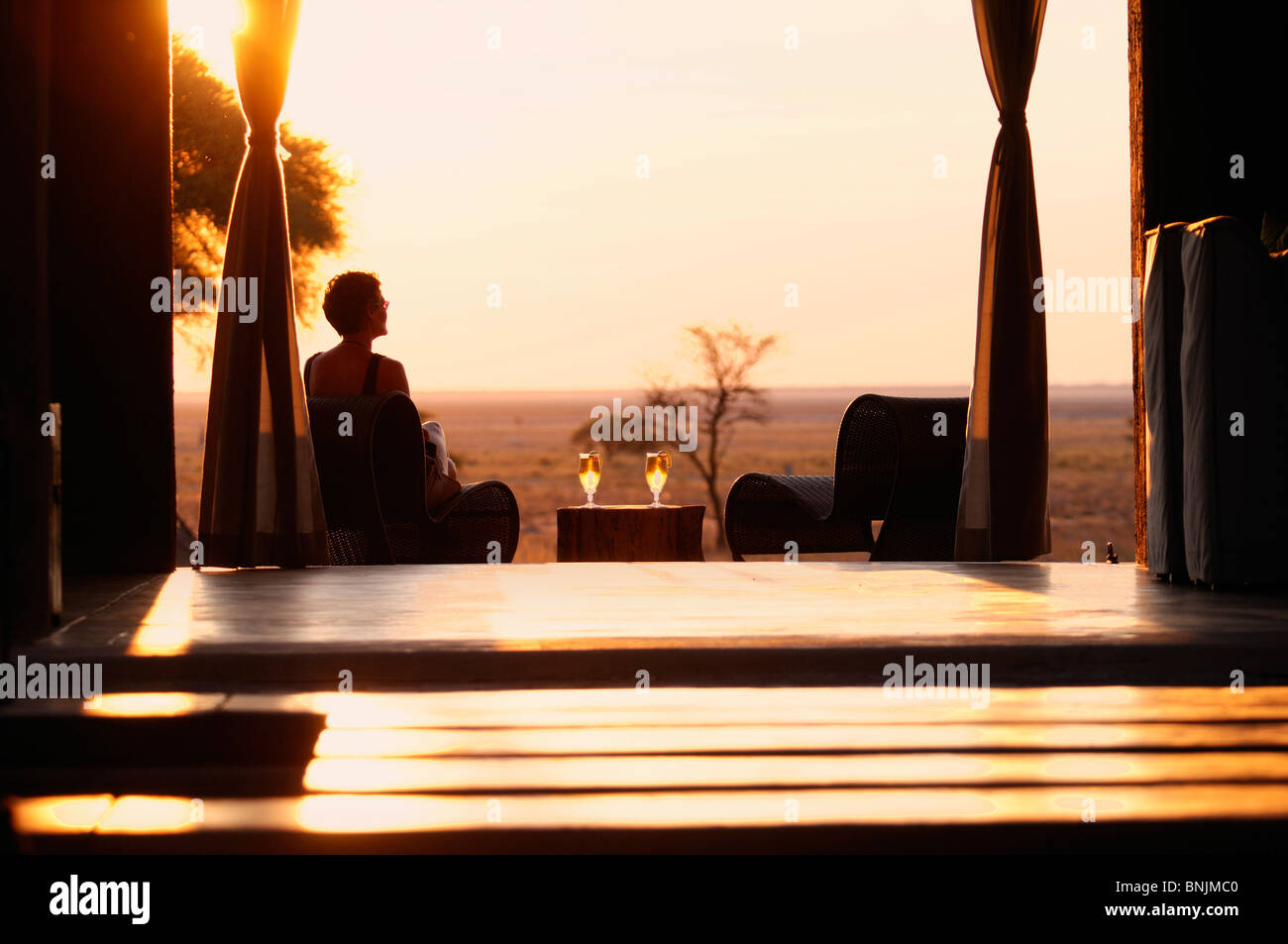 Sundowner Sonnenuntergang Drink serviert Frau deck The Fort Fisher Pan Onguma Safari Camp Etosha Nationalpark Kunene-Region Namibias Stockfoto