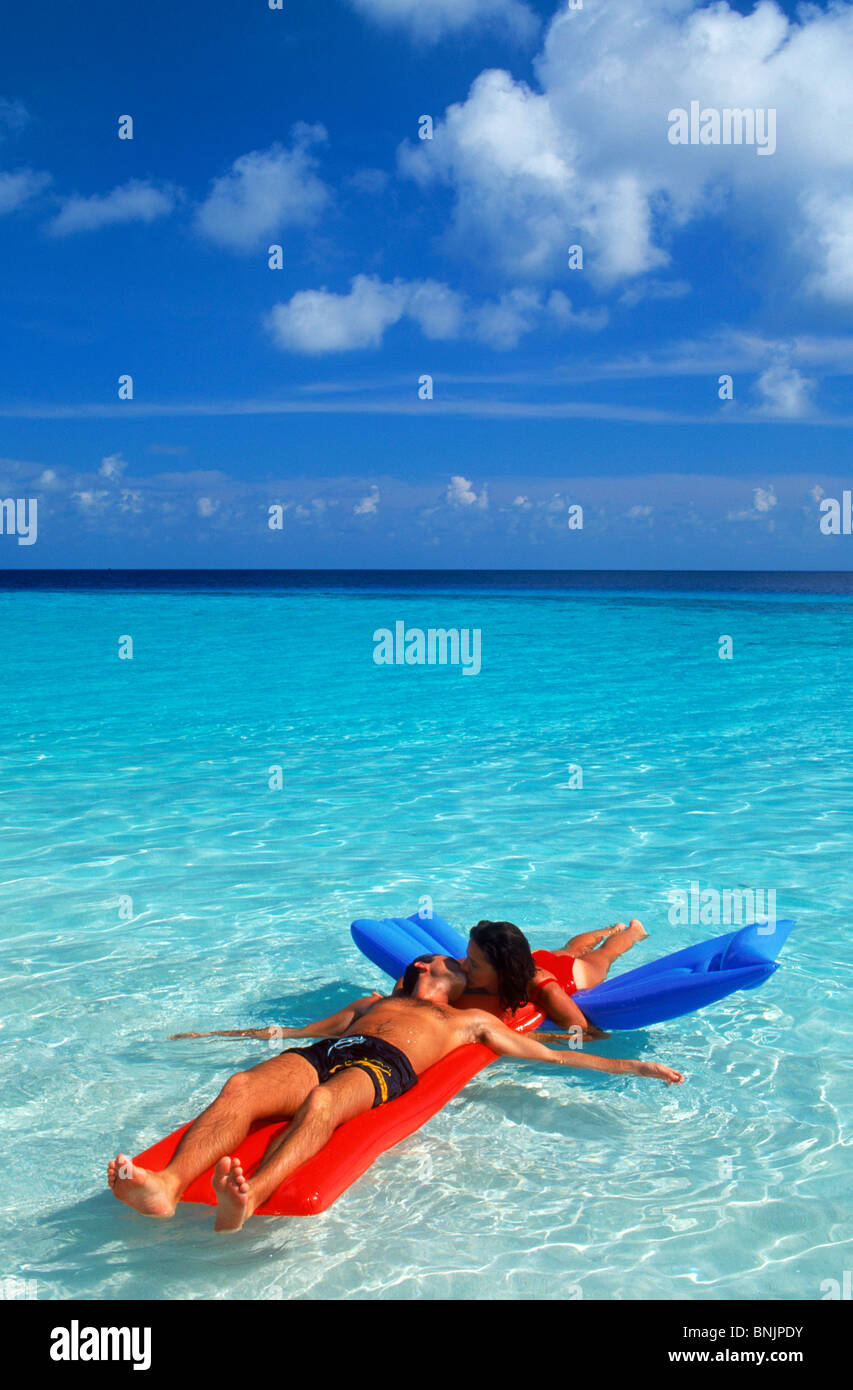 Paar in idyllische Inselurlaub im Paradies unter geschwollenen weiße Wolken auf bunte Luftmatratzen schweben Stockfoto