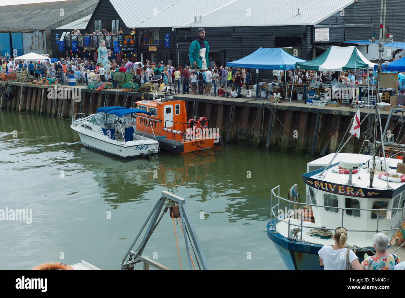 Riesen verläuft entlang des Hafens am Whitstable Oyster Festival von vielen Zuschauern beobachtet Stockfoto