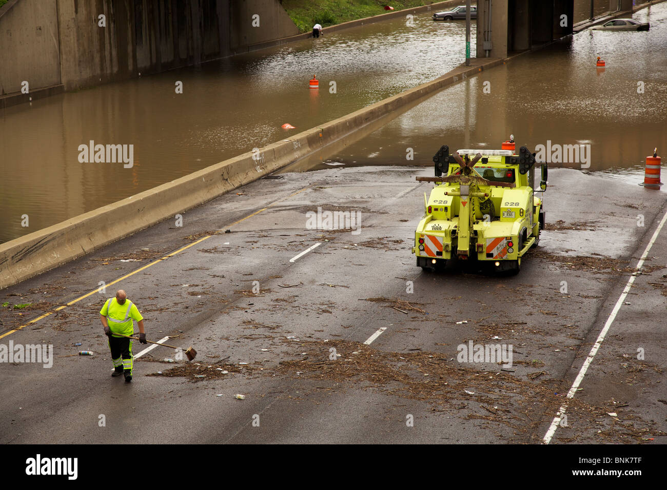 Autobahn Arbeitskraft löscht Trümmer Insterstate 290 nach einem schweren Hochwasser. Gestrandete Autos im Hintergrund. Stockfoto