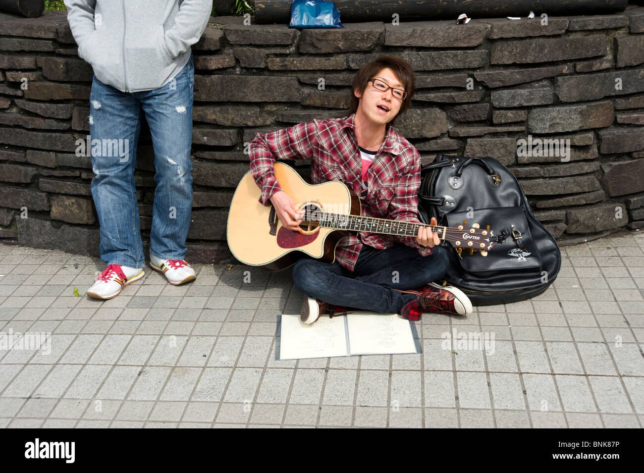 Jungen Straßenmusiker spielt Gitarre in Shinjuku, Tokyo, Japan Stockfoto