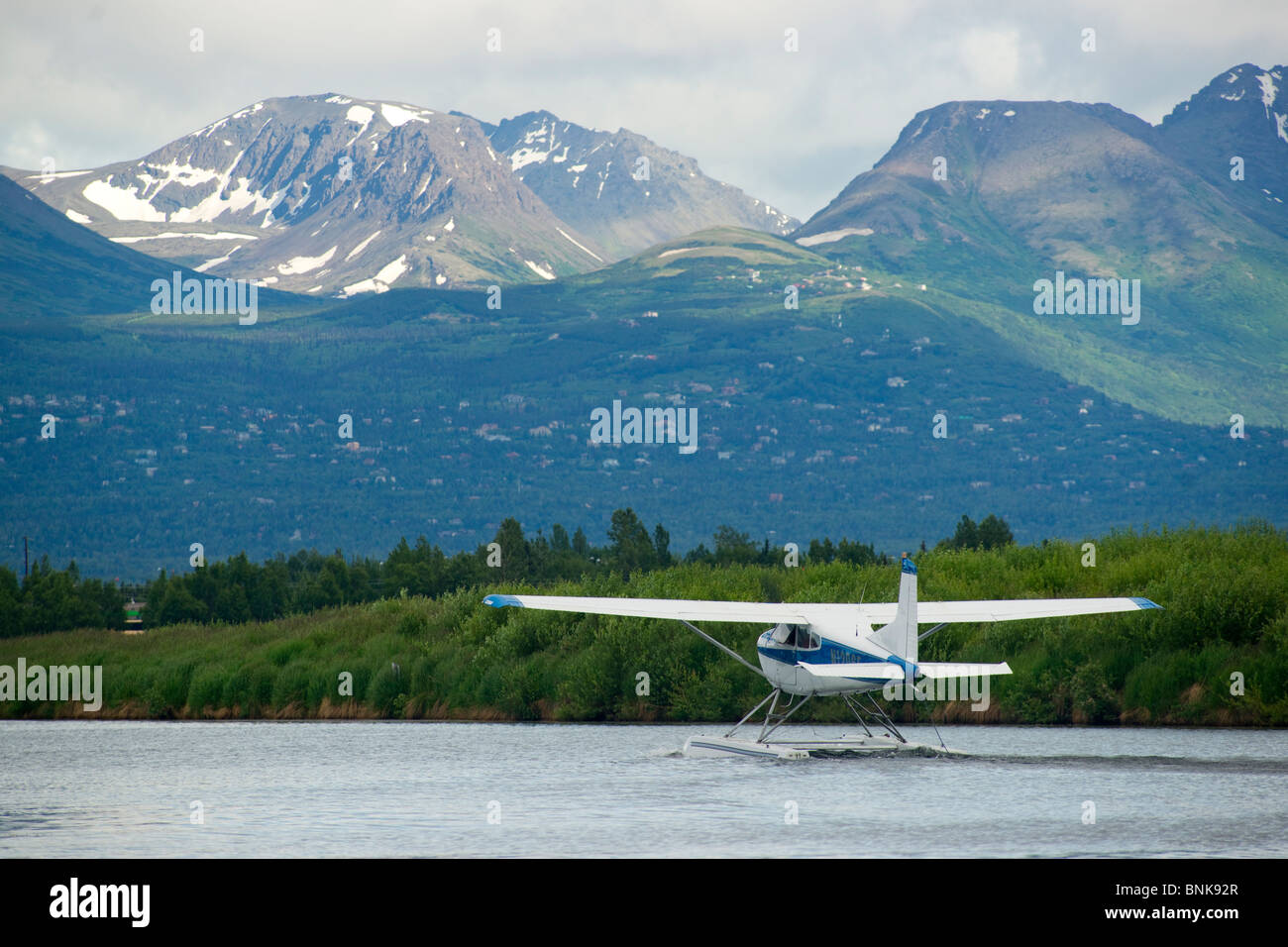 Ponton-Flugzeug fliegt von Lake Hood in Anchorage, umrahmt von den Chugach Mountains Stockfoto