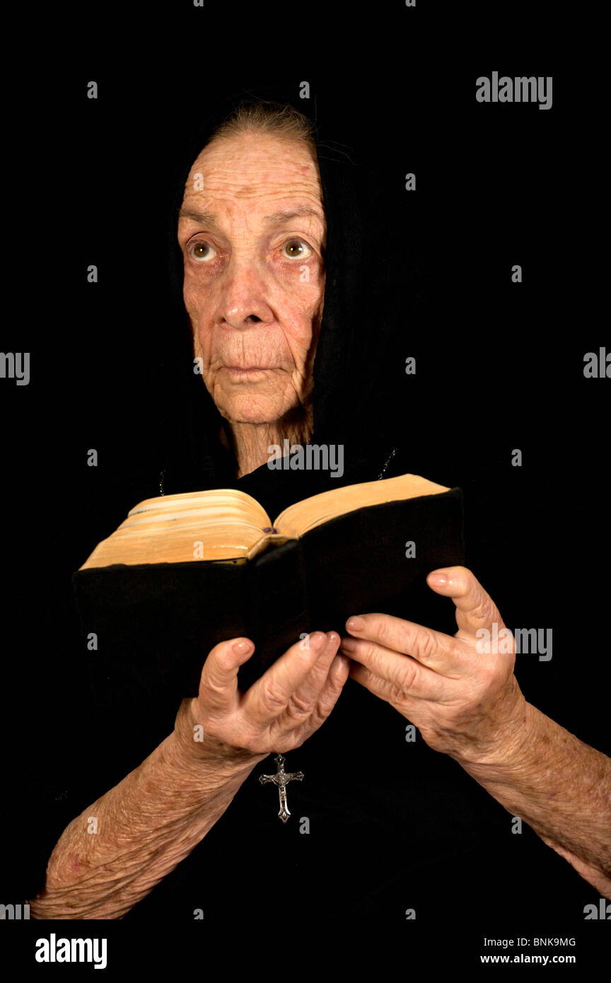 Alte Frauen tief im Gebet mit einer Bibel und Rosenkranz Stockfoto