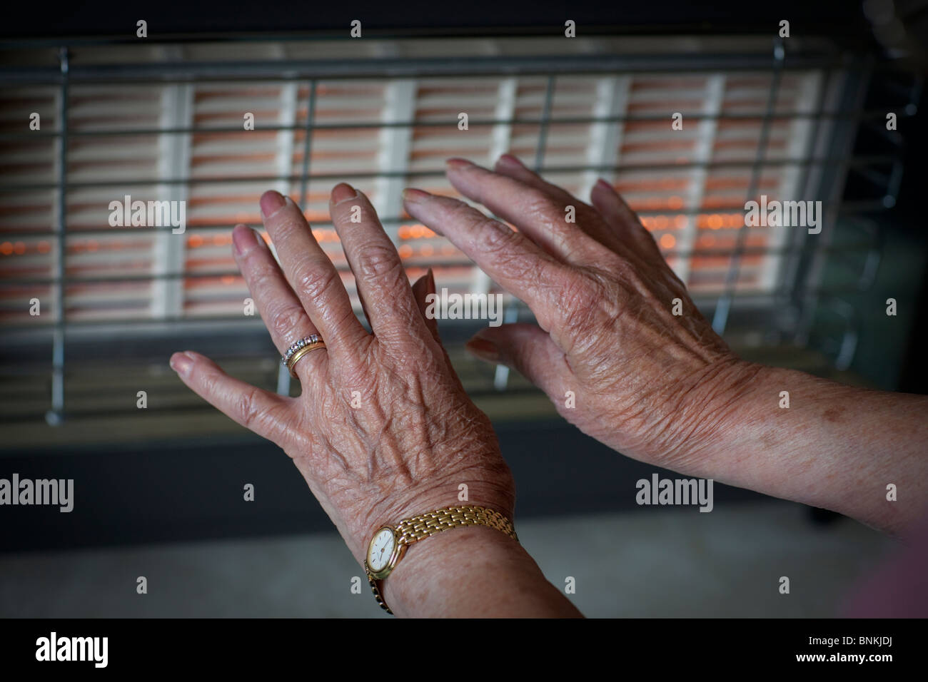 Die Hände von einem Rentner vor einem Gasfeuer, in den Wintermonaten warm zu halten Stockfoto