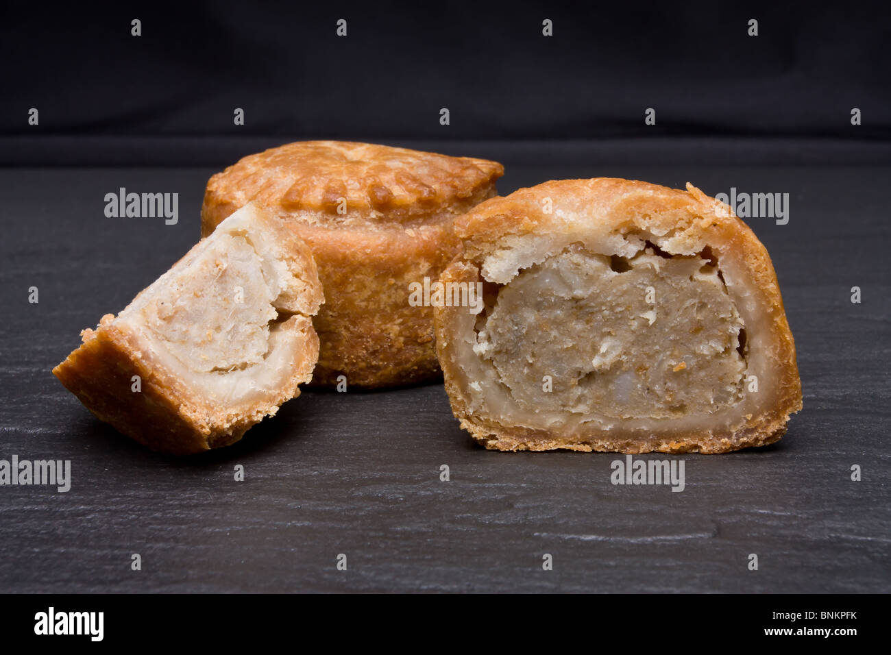 Traditionelle englische Pork Pie aus niedrigen Perspektive dunklen Schiefer Hintergrund. Stockfoto
