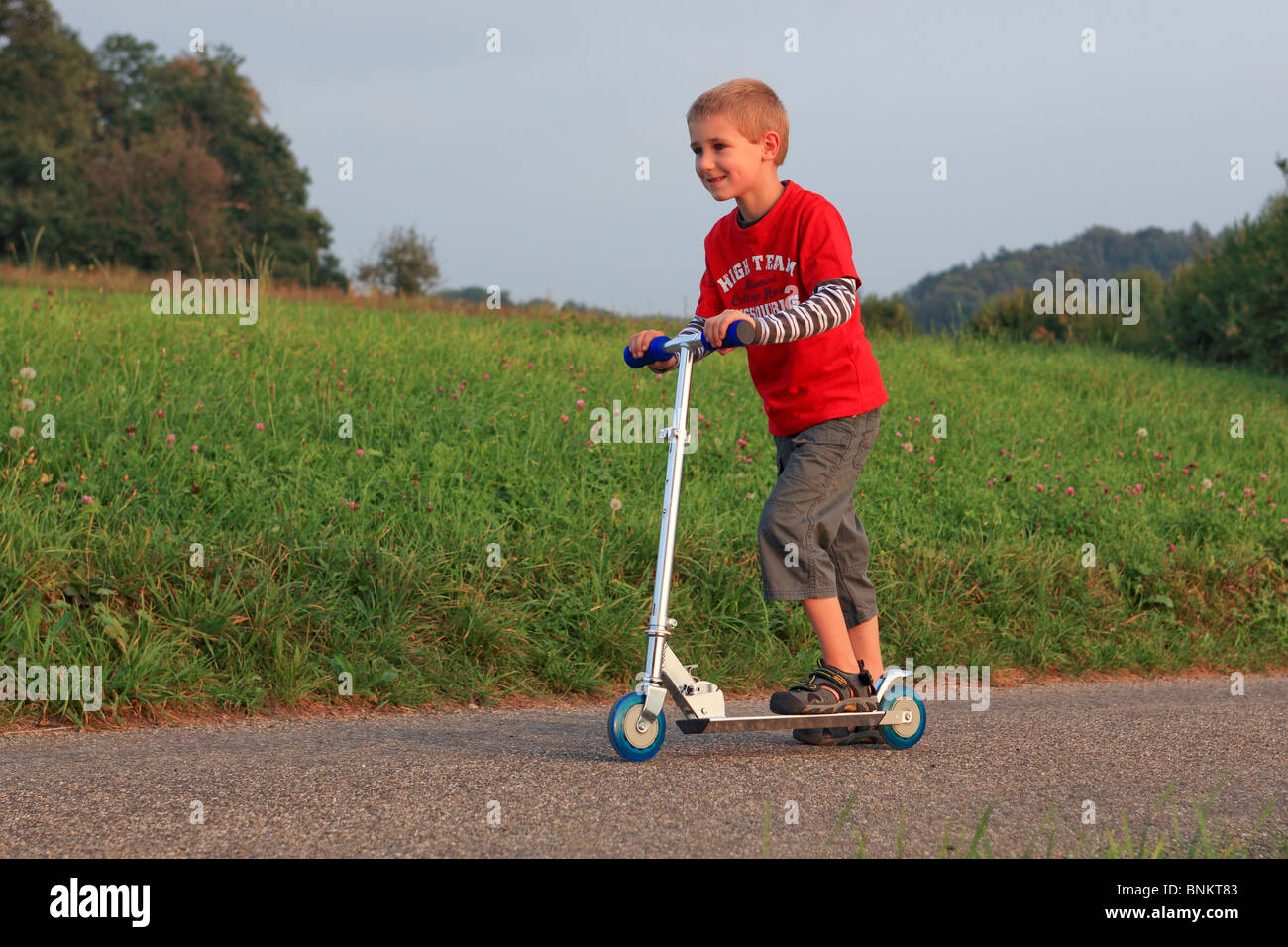 6 6-jährige Tätigkeit Bewegung junge Freude Geschwindigkeit Schnelligkeit Himmel Himmel junge Trottinet Scooter Kind junge Natur Spaß Witz Sport Tempo Stockfoto