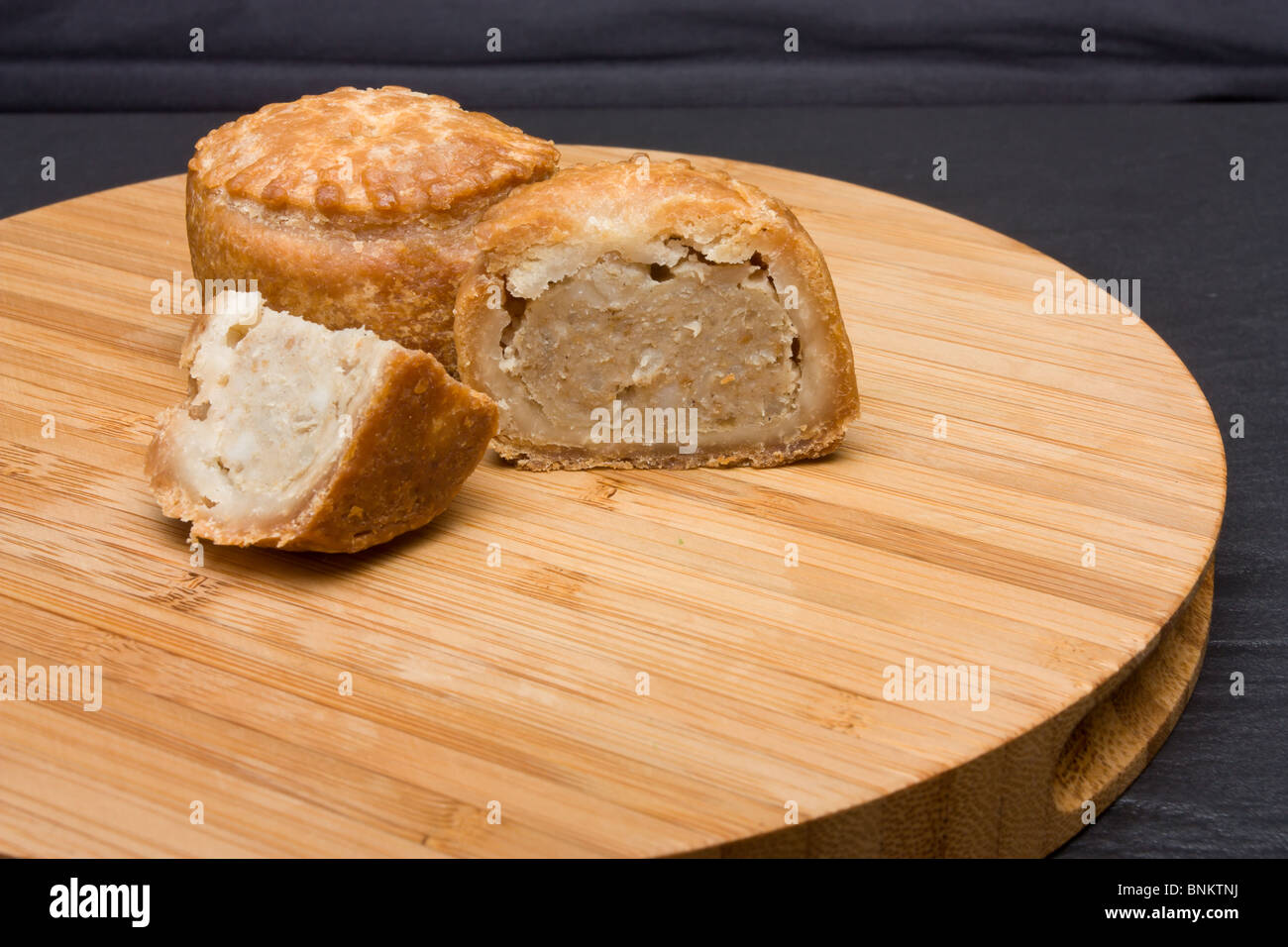 Traditionelle englische Pork Pie aus niedrigen Perspektive auf hölzernen Platte. Stockfoto