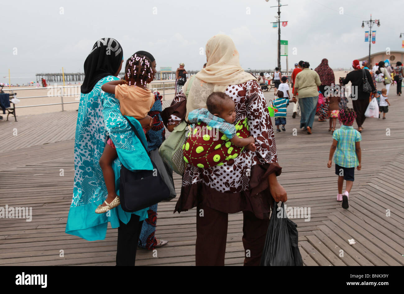 Muslimische Frauen, die entlang der Promenade von Coney Island mit Baby im papoose Stockfoto