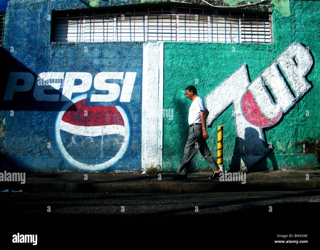 Ein Mann geht vorbei an Softdrinks, die Werbung auf einer Wand in Santo Domingo, Dominikanische Republik Stockfoto