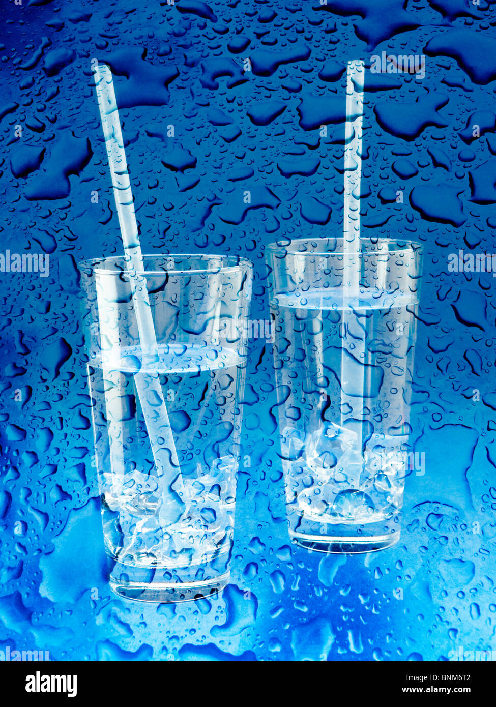 Zwei Gläser Wasser mit Trinkhalme mit Wassertropfen auf blauem Hintergrund Stockfoto