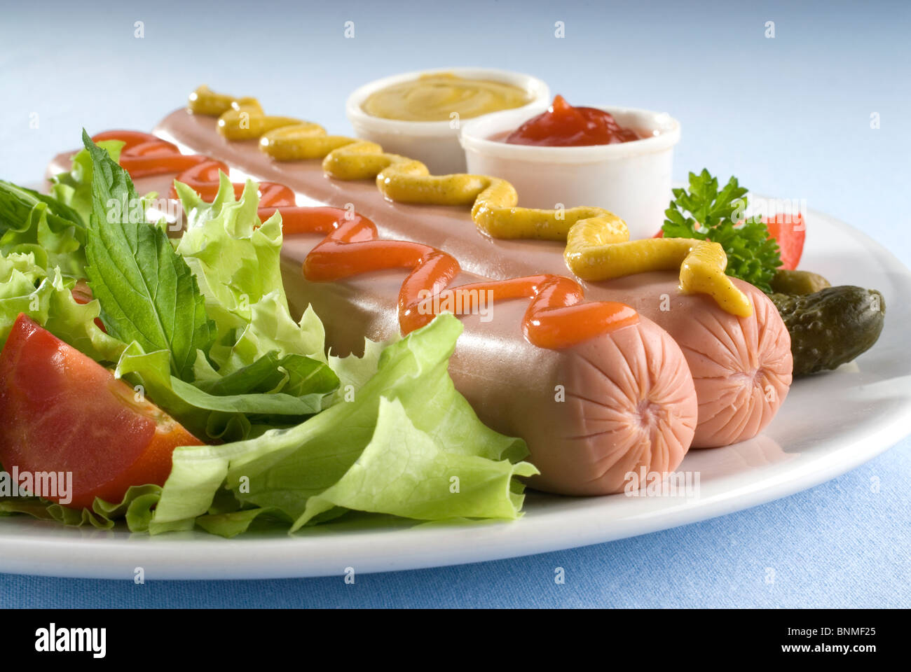essen Würstchen auf einem Teller mit Senf, Ketchup und Salat Stockfoto