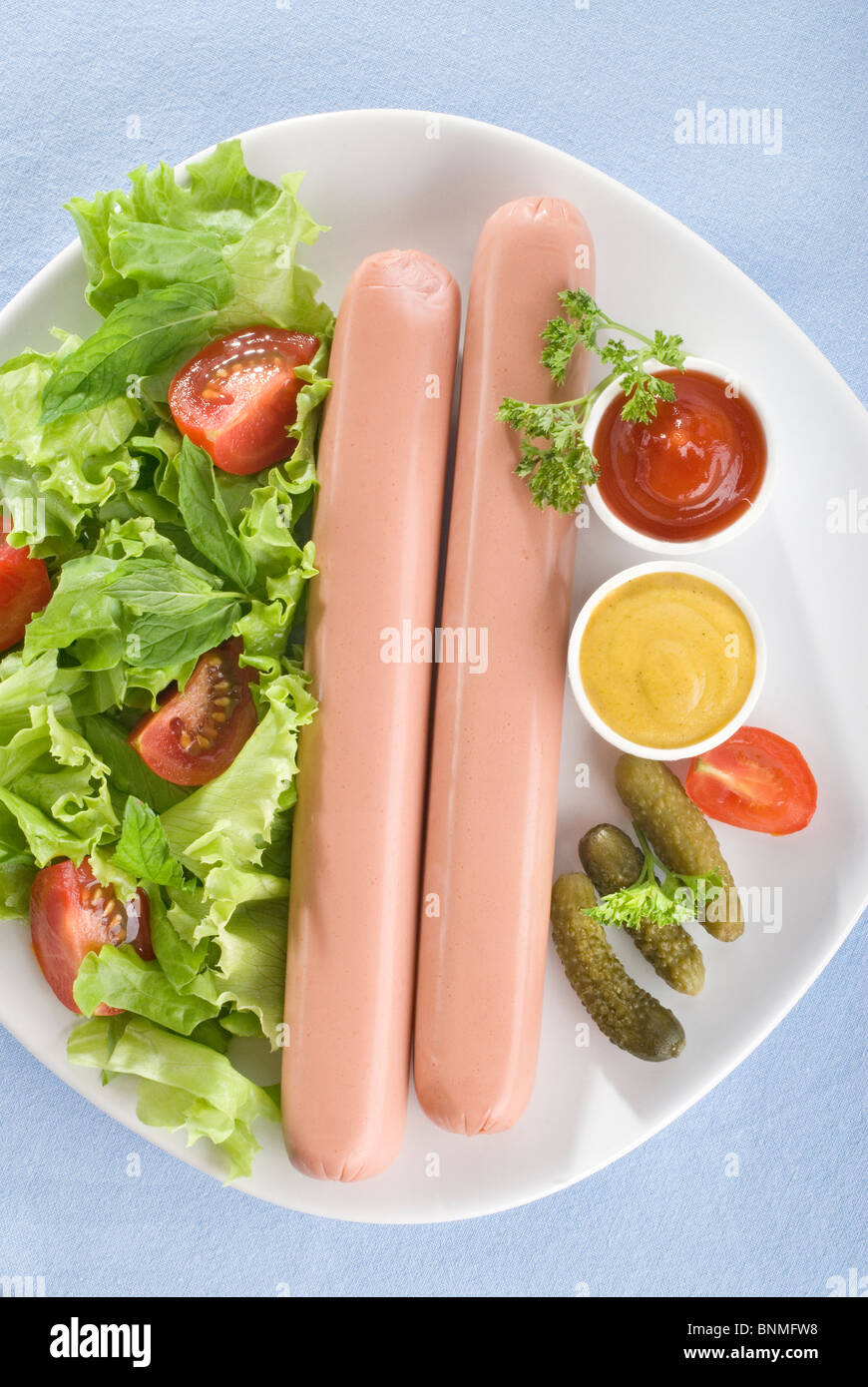 Würstchen, Salat, Ketchup, Senf, Gurken Stockfoto