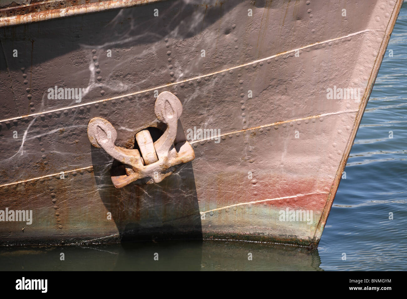 Bug und Anker eines alten genieteten Schiff mit dem Wasser reflektiert auf dem Rumpf. IJmuiden Hafen, Holland, Europa. Stockfoto