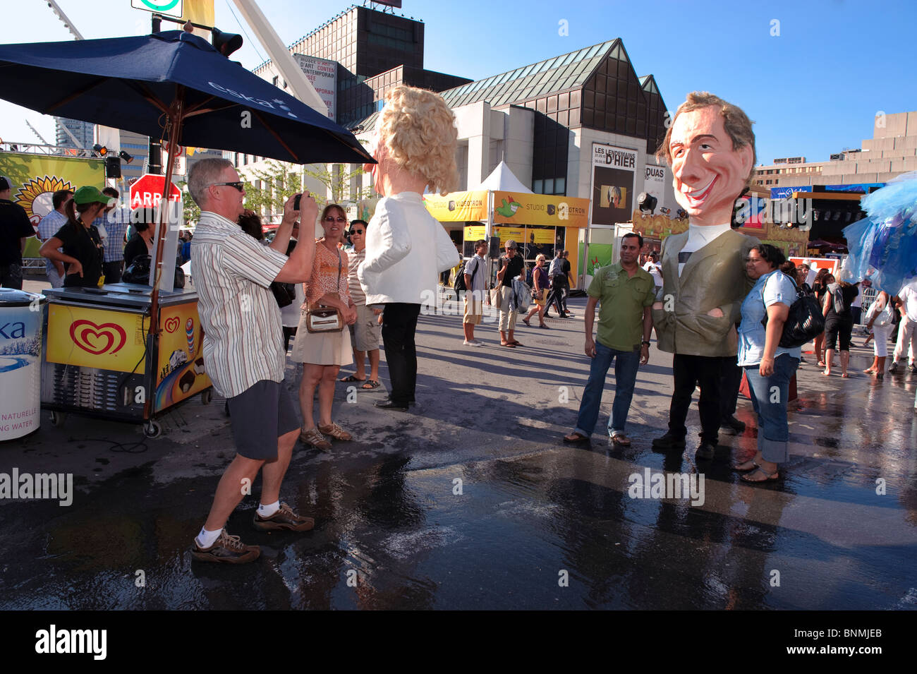 Mann, ein Bild von ein paar begleitet von einem riesigen Kopf Charakter während das Just für Laughs Festival in Montreal. Stockfoto