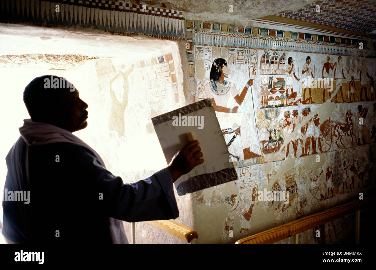 Hausmeister mit Hilfe von spiegeln das Sonnenlicht in das Grab des Menna (Nr. 69) umleiten auf das Tal des Adels in Luxor. Stockfoto