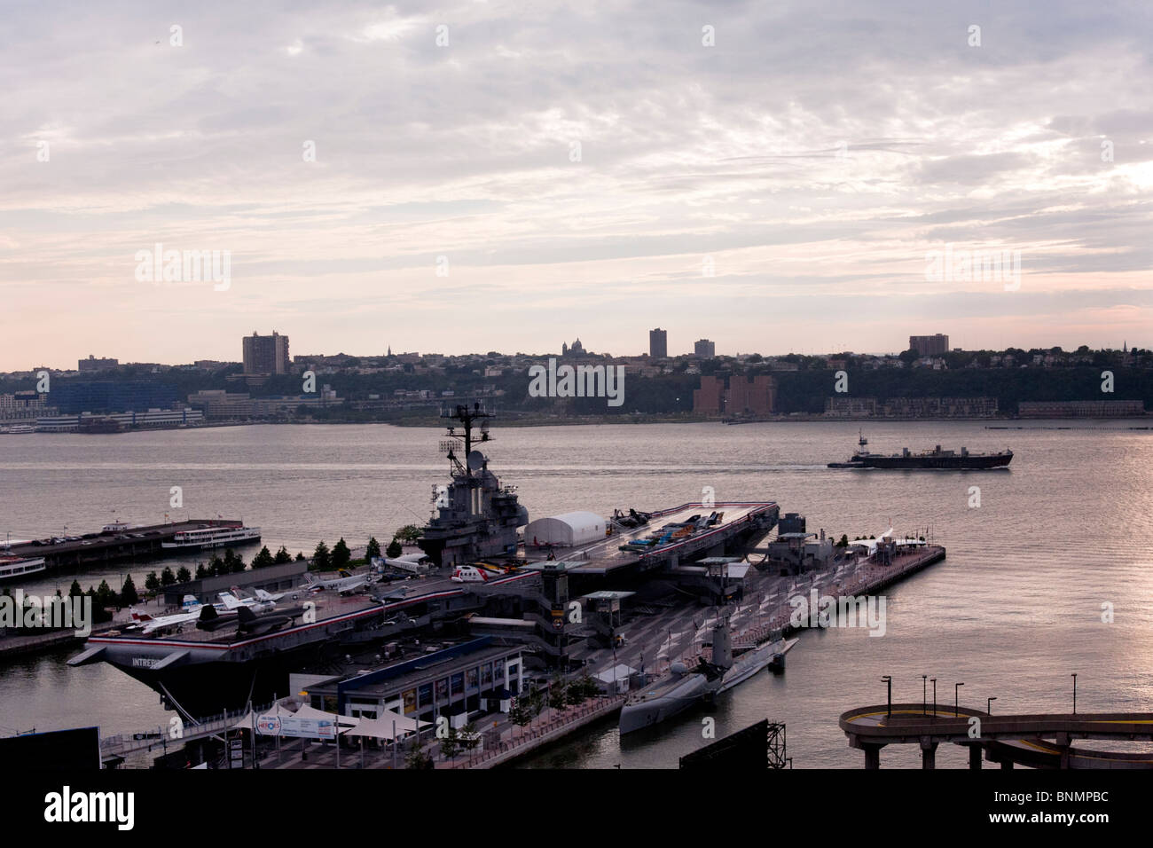 Blick auf den Fluss von West Side Manhattan von Intrepid Museum Schiffsanlegestelle, vorbei an Schlepper Jersey Palisades Lastkahn & untergehende Sonne umstoßen Stockfoto